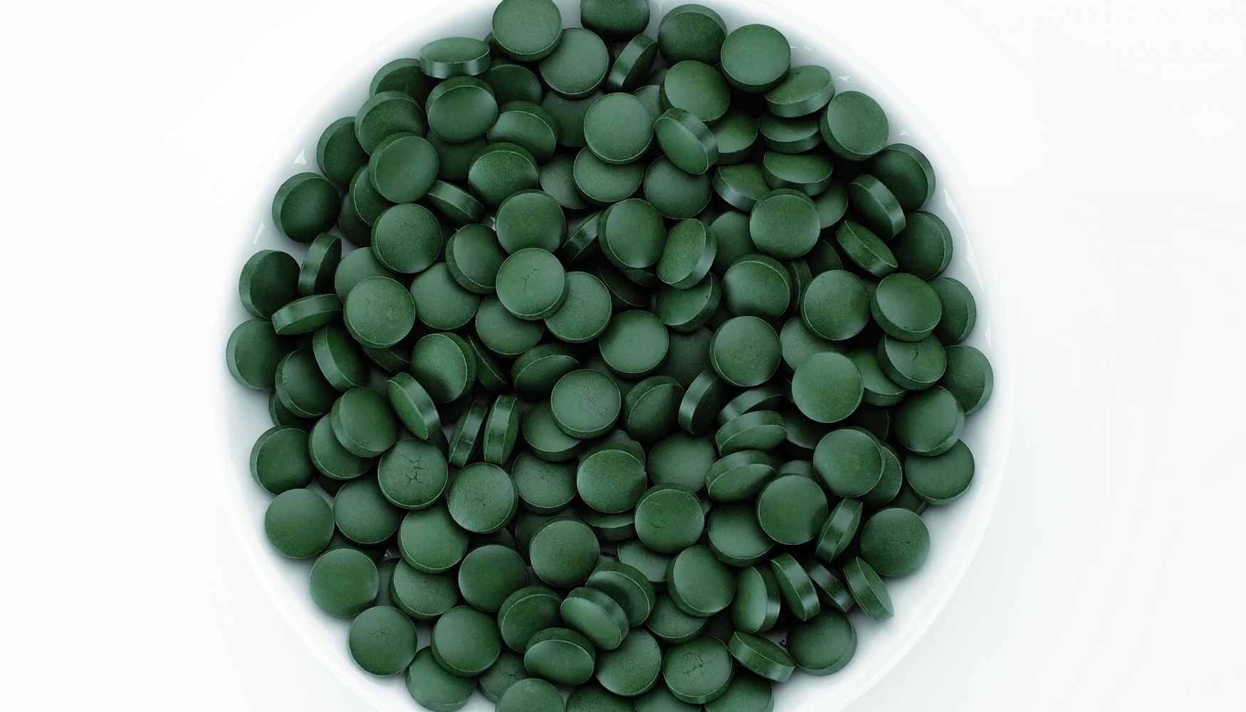 close up of chlorella spirulina tablets in a white bowl