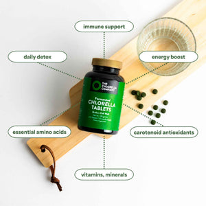 Bottle of fermented Chlorella tablets with health benefits listed on a wooden board